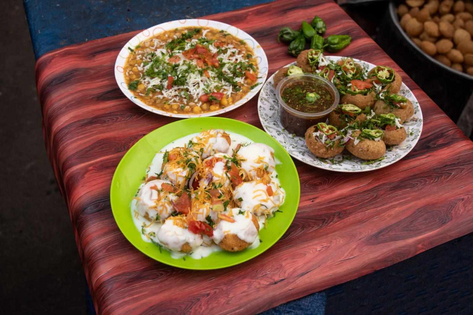Spicy Chotpoti, plain or Doi Fuchka, pan puri, or gol gappa filled with herbs with spicy water served in plate isolated on wooden table side view of bangladeshi street food
