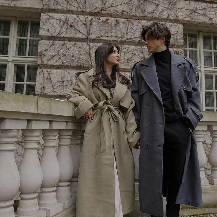 This may contain: two people standing next to each other in front of a building