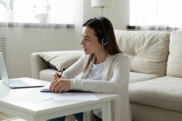 Focused woman in headphones watch webinar on laptop writing notes Young serious focused woman in headphones watch webinar use laptop writing notes. E-learn process, self distant education, online course and tutoring, web training, study on computer at home concept teacher assistant online courses stock pictures, royalty-free photos & images