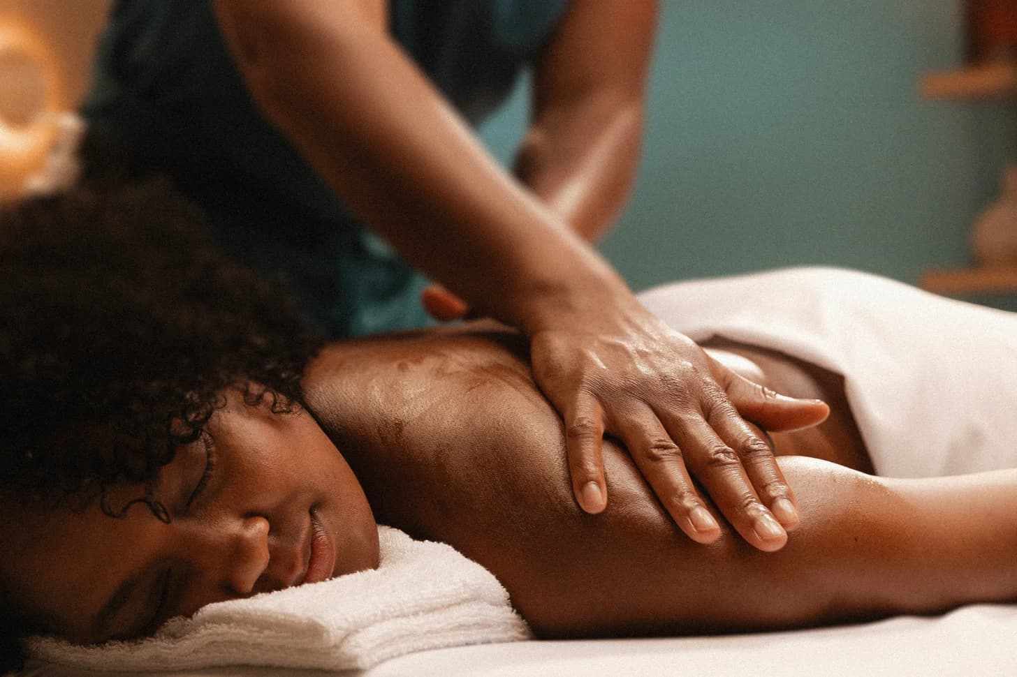 Woman with a soft smile, eyes closed and at ease, receiving a classic back massage