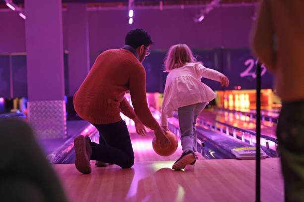 Family at bowling alley Father and daughter bowl ball in bowling alley, pink light on bowling alley bowling  stock pictures, royalty-free photos & images