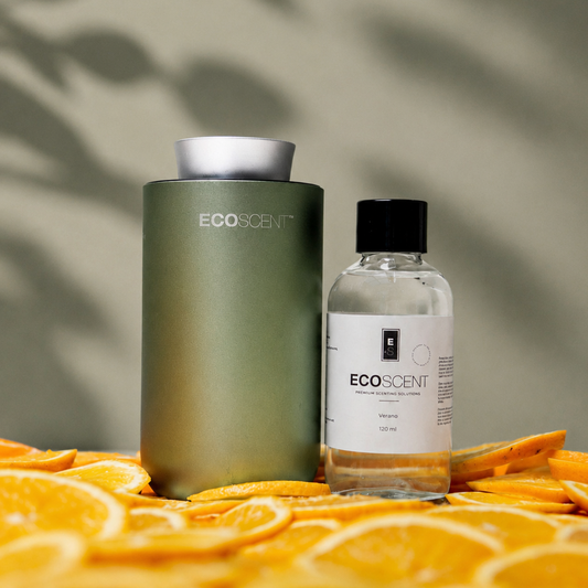 Two Ecoscent products on a surface with orange slices and a leafy background