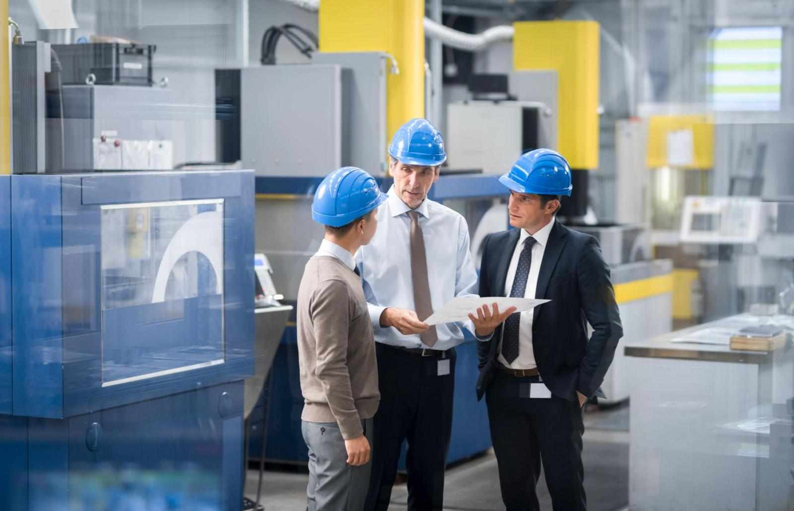 Engineers and manager discussing engineering drawing