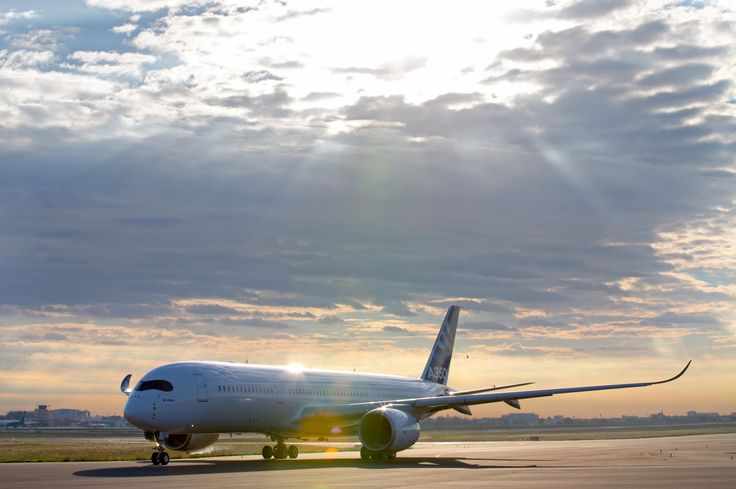 This may contain: an airplane is sitting on the tarmac under a cloudy sky with sunbeams