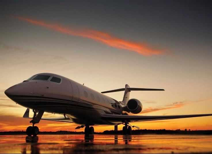 This may contain: an airplane is sitting on the tarmac at sunset