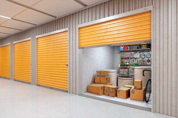 Self-Storage Facility Interior with Tools An organized self-storage facility featuring orange storage doors.Inside the unit  a bicycle leaning against the wall, cardboard boxes, and an array of tools displayed. Garage door supply  stock pictures, royalty-free photos & images