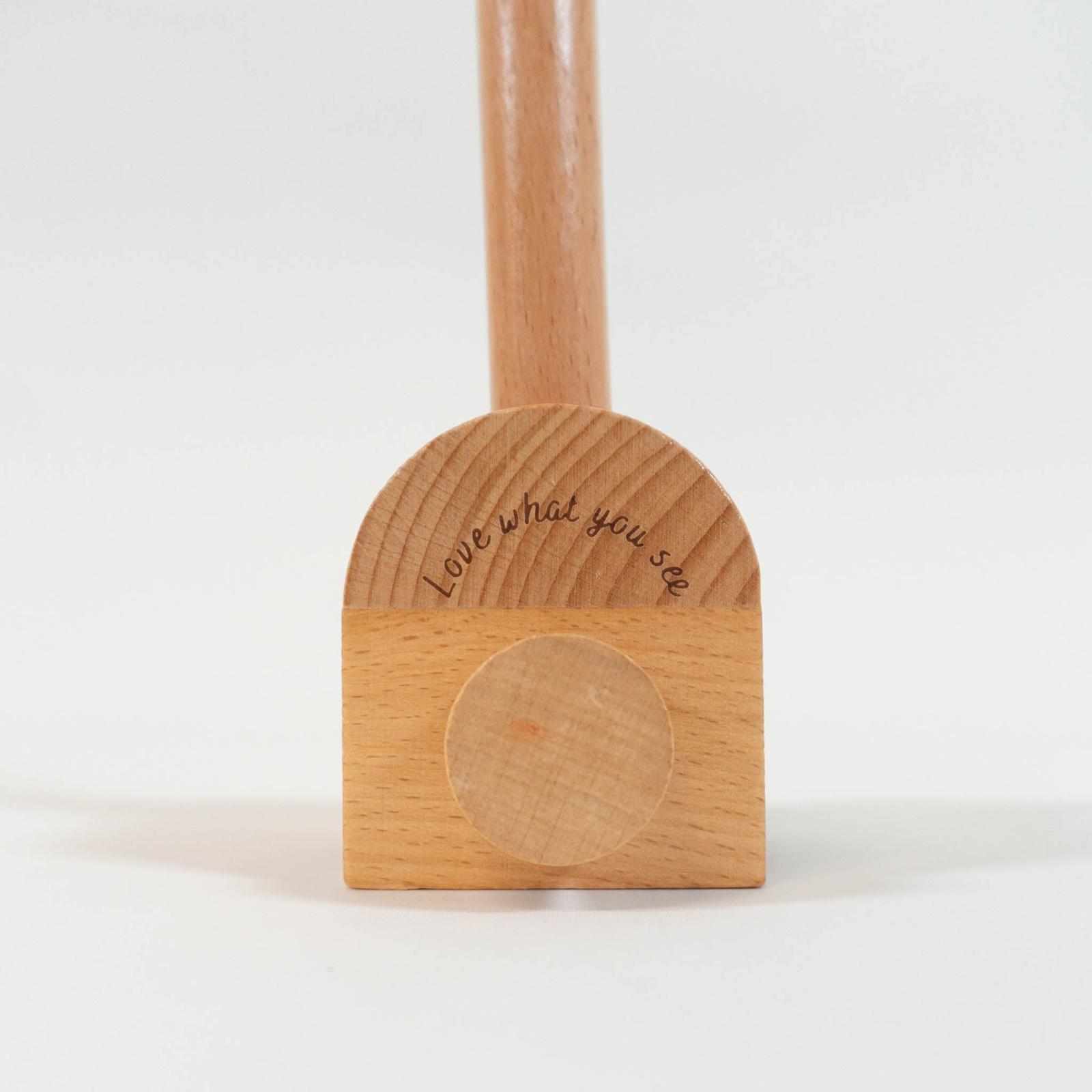 A zoomed in view of the base of the wooden mobile arm with the engraving "love what you see".