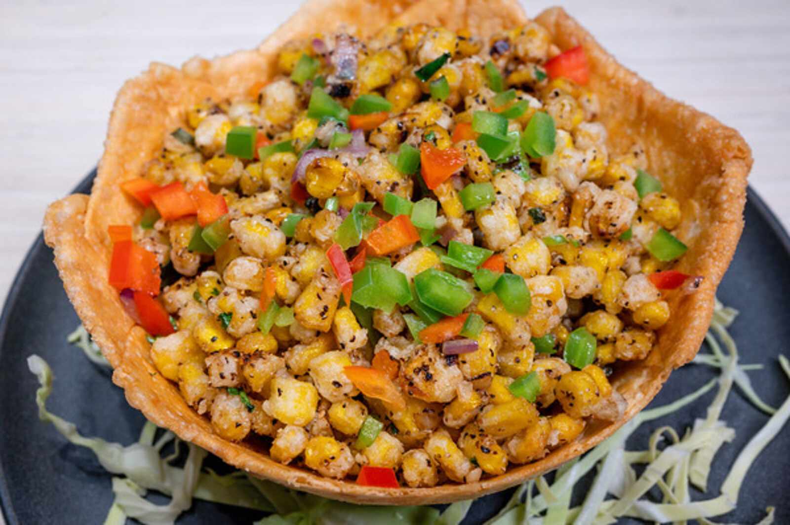 Caption: a black plate topped with a corn salad