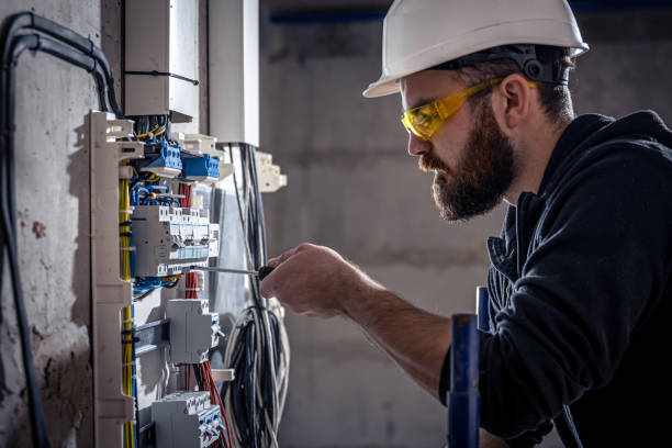 A male electrician works in a switchboard with an electrical connecting cable. A male electrician works in a switchboard with an electrical connecting cable, connects the equipment with tools. Electrician  stock pictures, royalty-free photos & images