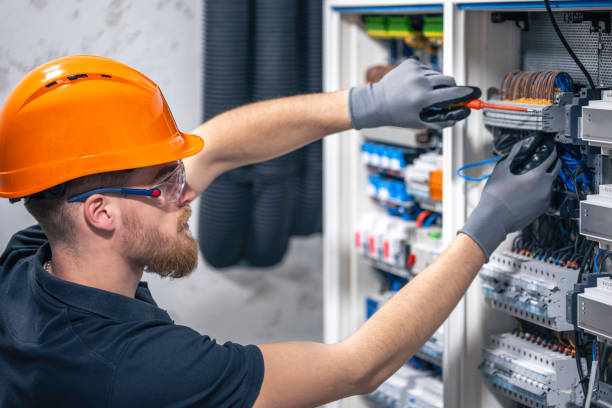 Male electrician working in a switchboard with fuses. A male electrician works in a switchboard with an electrical connecting cable. electrician  stock pictures, royalty-free photos & images