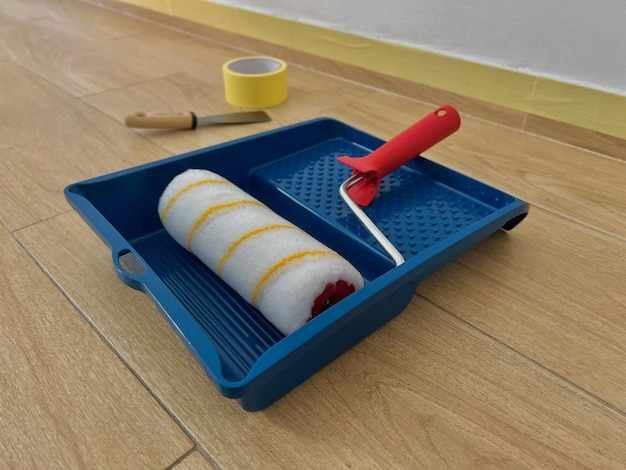 Closeup view of a tool kit for surfaces paint roller paint brushes masking tape laying on floor