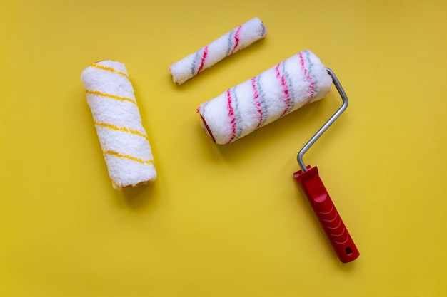 High angle view different paint rollers on yellow background hardware shop decor design concept