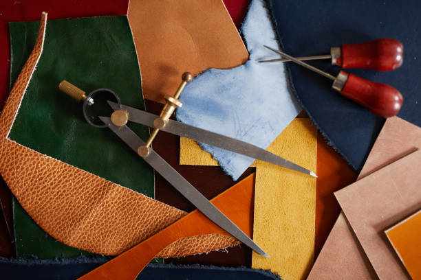 Leatherwork Background Background image of leather cuts and tools scattered on table in tanners workshop, copy space sewing cutting table stock pictures, royalty-free photos & images