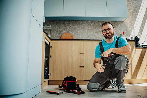 Professional plumber posing in kitchen Male plumber kneeling with tools in front, ready to fix plumbing issue in modern kitchen plumber stock pictures, royalty-free photos & images