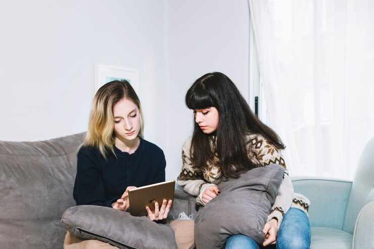 Young girls using tablet on couch