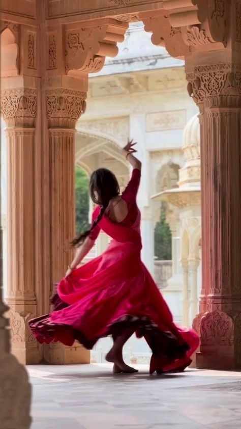 This may contain: a woman in a long red dress is dancing on the floor with her arms outstretched