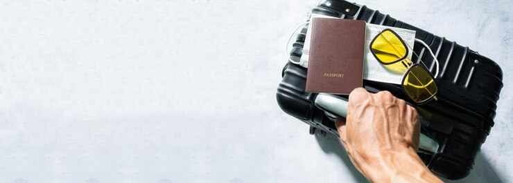 LuggageSuitcase passport and medical maskHand holding passport and approved vaccination card