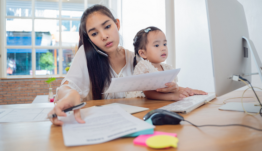 Working mother balancing work and childcare while holding her child