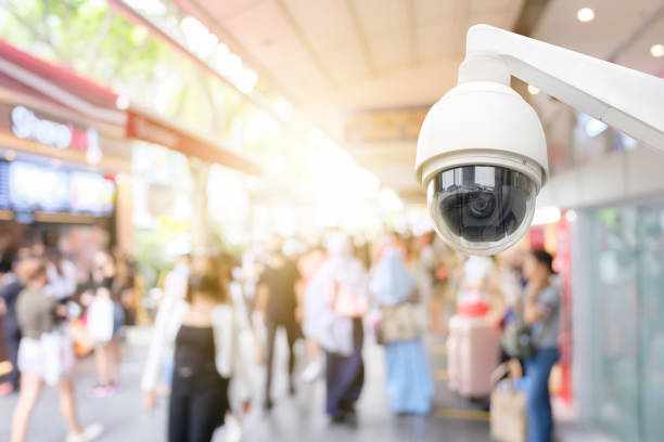 Modern public CCTV camera with blur crowd and shopping plaza background. Recording cameras for monitoring all day and night. Concept of surveillance and monitoring with copy space. Modern public CCTV camera with blur crowd and shopping plaza background. Recording cameras for monitoring all day and night. Concept of surveillance and monitoring with copy space. cctv for crowd stock pictures, royalty-free photos & images