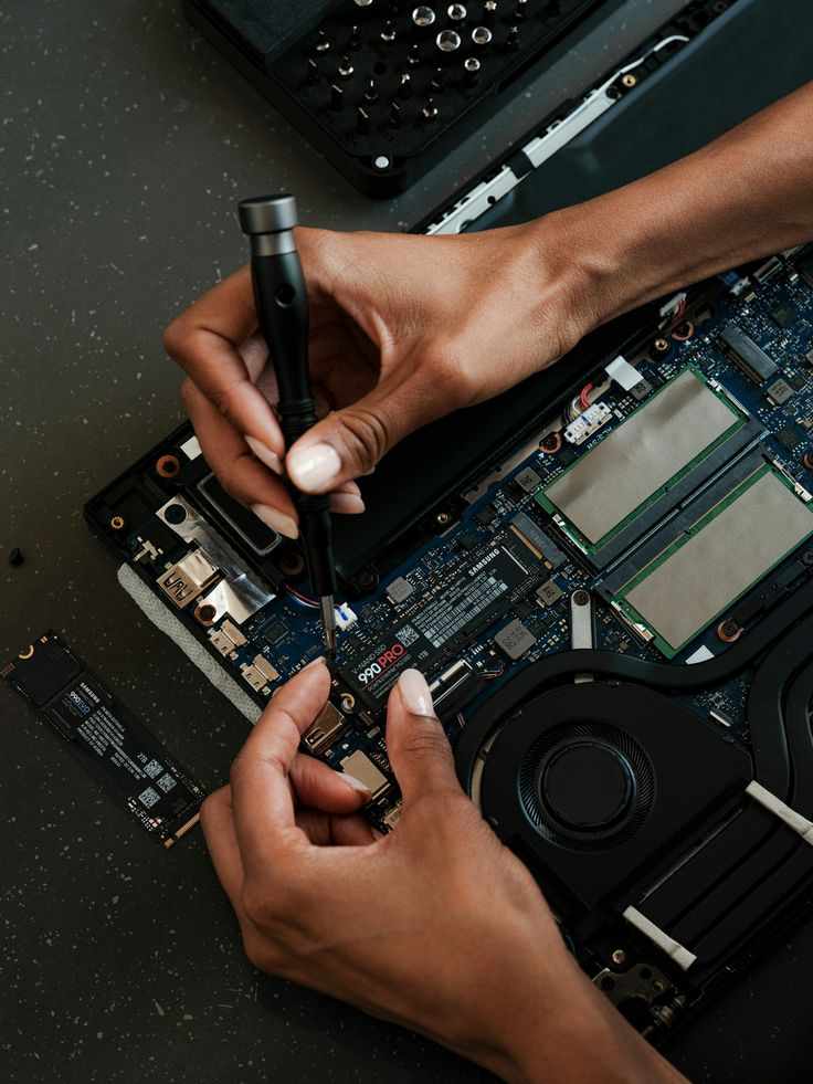 This may contain: two hands are working on the motherboard of a laptop