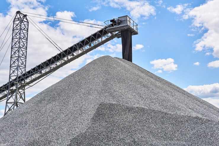 Huge pile of gravel and conveyor belt loader against the sky