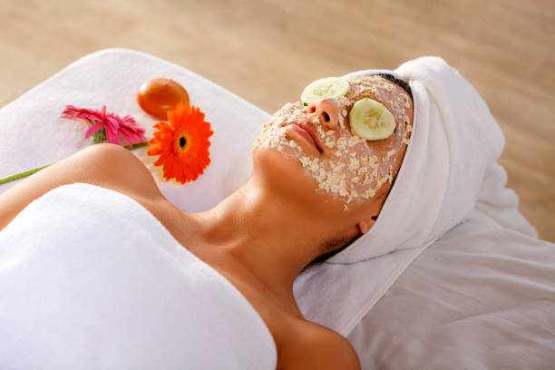 Hispanic young woman laying on bed and getting oatmeal face scrub and resting with cucumber slices on eyes. Hispanic young woman laying on bed and getting oatmeal face scrub and resting with cucumber slices on eyes. Facial treatments  stock pictures, royalty-free photos & images