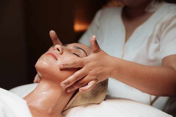 Woman receiving a rejuvenating facial mask treatment from a skilled professional at a health and wellness center Woman receiving a rejuvenating facial mask treatment from a skilled professional at a health and wellness center, as nourishing ingredients work to hydrate, brighten, and rejuvenate her skin, restoring a radiant and youthful glow and enhancing her natural beauty Facial treatments  stock pictures, royalty-free photos & images