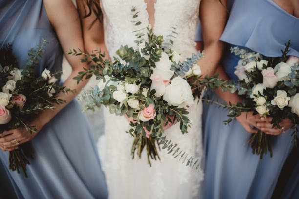 Bride and bridesmaids holding bouquets of flowers Bride and bridesmaids in blue dresses with bunches of white roses bridal dress usa stock pictures, royalty-free photos & images