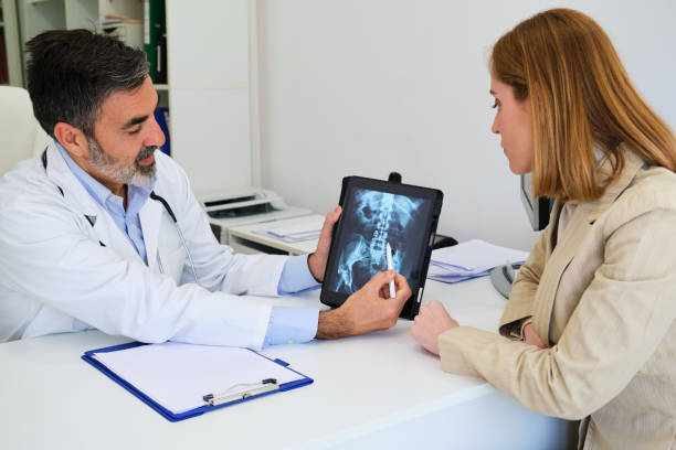 Doctor explaining x-ray to his female patient after surgery for a broken hip. Doctor explaining x-ray to his female patient after surgery for a broken hip. Healthcare and medicine. spine Clinic stock pictures, royalty-free photos & images
