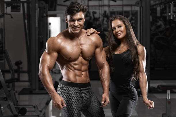 Sporty beautiful couple showing muscle and workout in gym. Muscular man and woman Sporty beautiful couple showing muscle and workout in gym. Muscular man and woman men and women muscle builder stock pictures, royalty-free photos & images