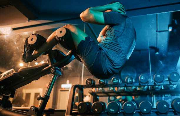 low angle view asian indian macho male athlete sit -ups workout at gym at night with weight bench low angle view asian indian macho male athlete sit -ups workout at gym at night with weight bench men bodybuilder stock pictures, royalty-free photos & images