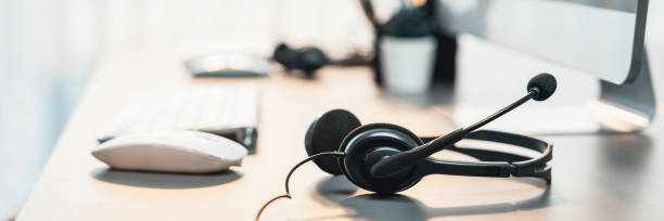 Panorama view of empty call center operator workspace focus on headset. Prodigy