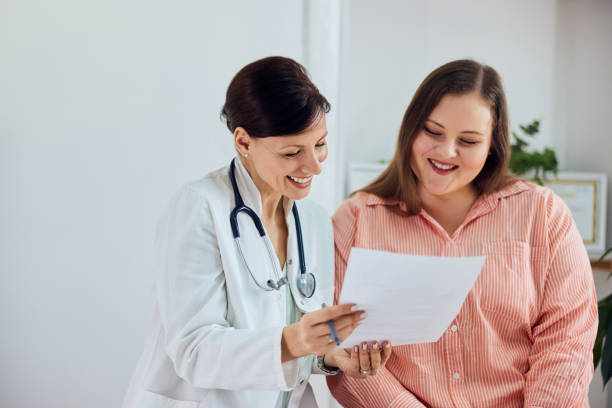 A smiling female nutritionist showing good progress results to a happy overweight patient. A happy overweight woman is satisfied with her weight loss program results and sitting with a female nutritionist. medical appointment stock pictures, royalty-free photos & images