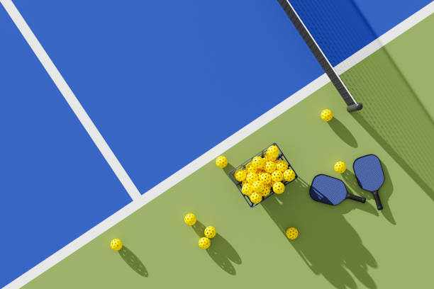Two Pickleball paddles and basket of balls on court. Top view. 3d illustration, render. Two Pickleball paddles and basket of balls on court. Top view. 3d illustration, render. pickleball court stock illustrations